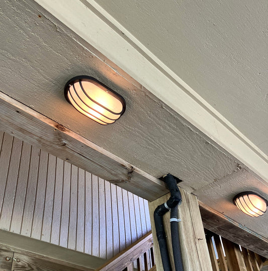 Corroded black oval outdoor light fixture beneath a Galveston West End beach home before replacement
